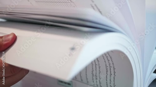 Slow motion of a man is opening large books to find information by trying to open many pages quickly on the table.