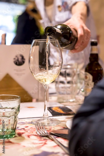 Sommelier pours wine into a glass of restaurant guests at dinner