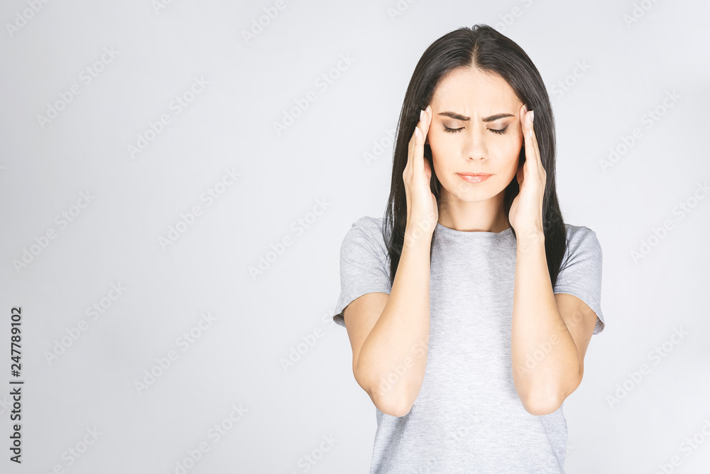 Portrait of beautiful young brunette with bare shoulders touching her temples feeling stress, isolated over white background. Portrait of beautiful young brunette with bare shoulders touching her temples feeling stress, isolated over white background.