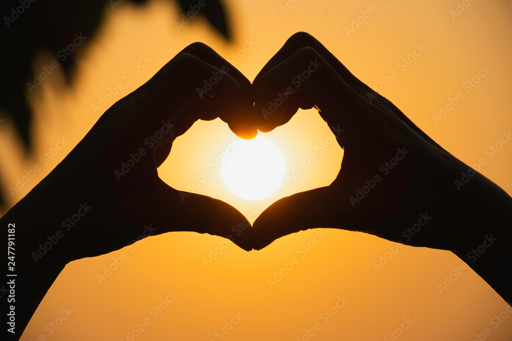 Fototapeta premium Hands of person make heart by finger in silhouette sunset background.