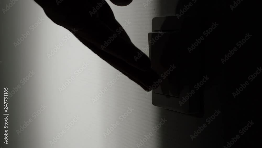 Man turning on the light with a switch on the wall
