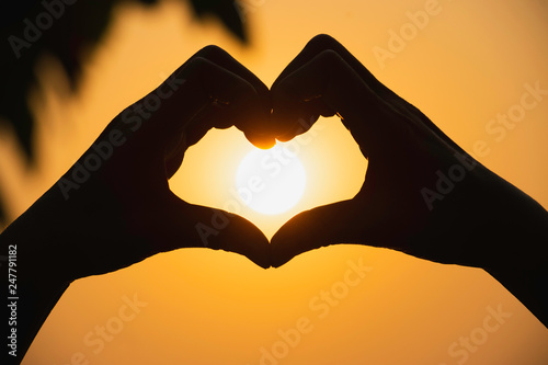 Hands of person make  heart by finger in silhouette sunset  background.