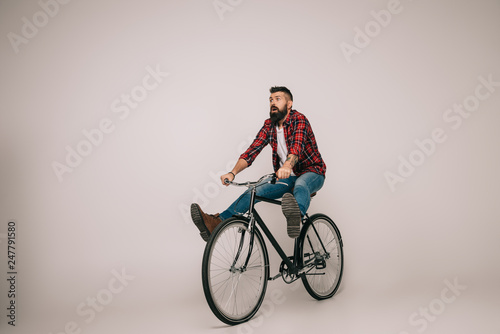 Fototapeta Naklejka Na Ścianę i Meble -  bearded excited man riding bike isolated on grey