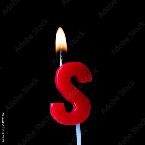 Letter S celebration birthday candle against a black background