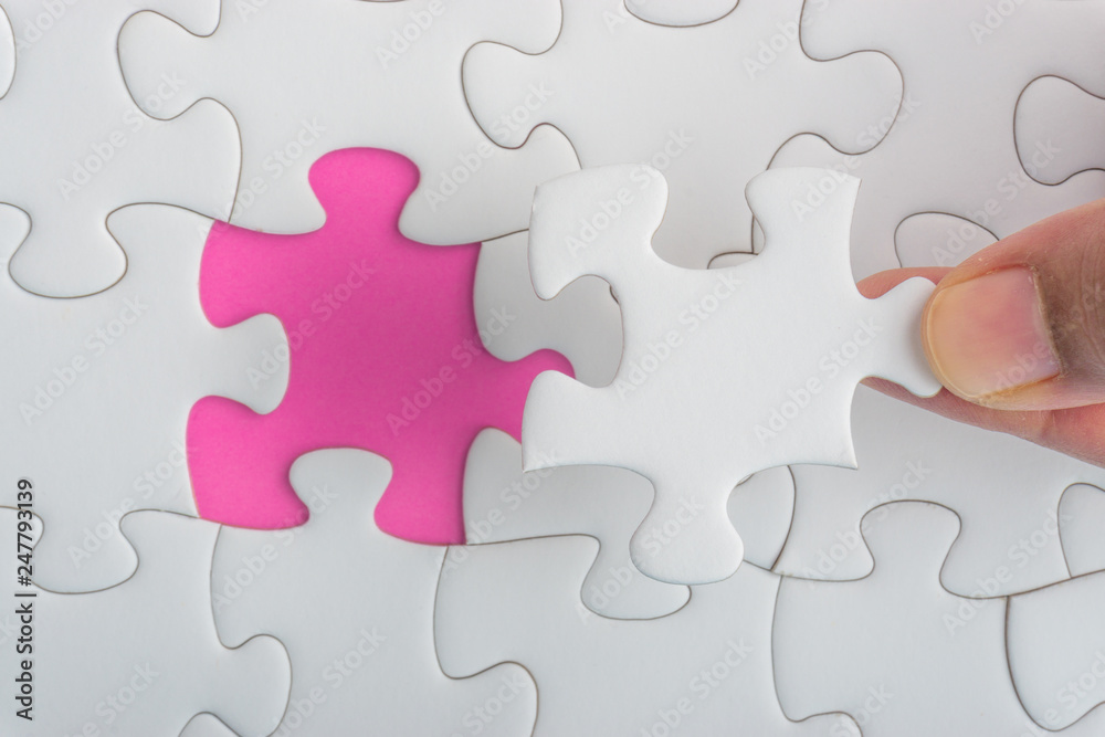 Hand put the last piece of jigsaw puzzle closeup to complete the mission. Selective focus and crop fragment Hand put the last piece of jigsaw puzzle closeup to complete the mission. Selective focus and crop fragment