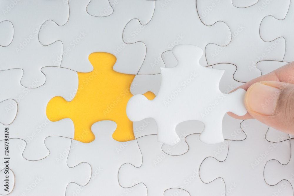 Hand put the last piece of jigsaw puzzle closeup to complete the mission. Selective focus and crop fragment Hand put the last piece of jigsaw puzzle closeup to complete the mission. Selective focus and crop fragment