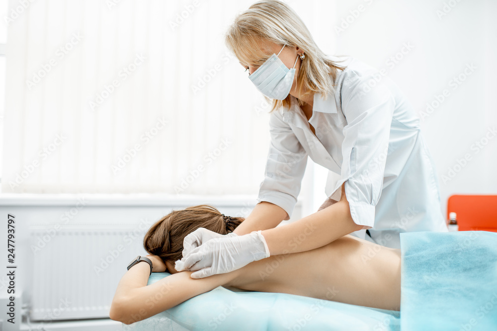 Neuropathologist puts needles into the woman's back removing inflammation of the muscles during the acupuncture treatment in the office Neuropathologist puts needles into the woman's back removing inflammation of the muscles during the acupuncture treatment in the office