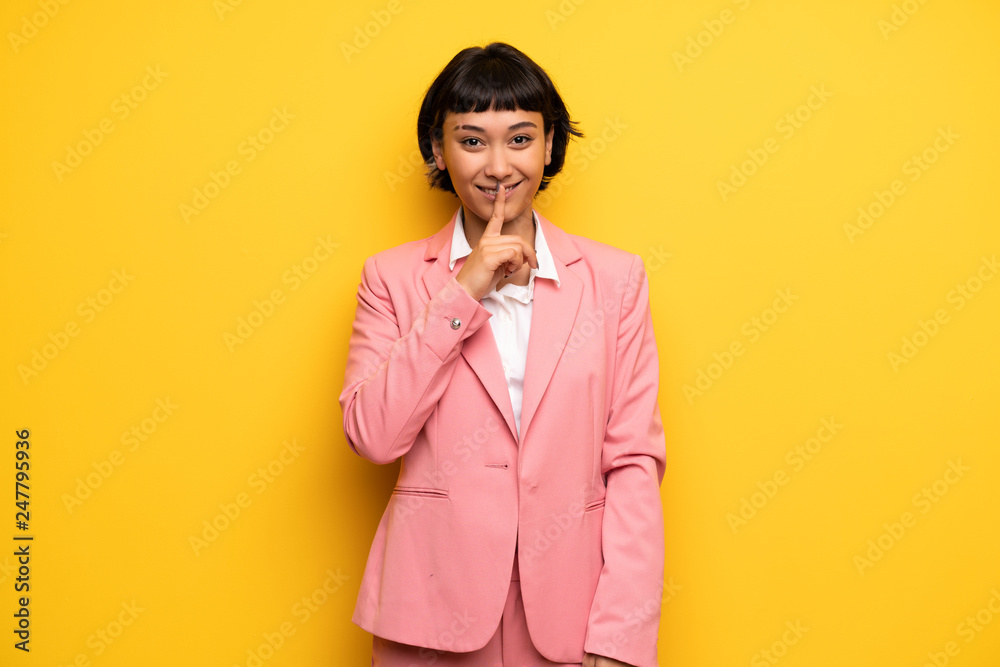 Modern woman with pink business suit showing a sign of silence gesture Modern woman with pink business suit showing a sign of silence gesture