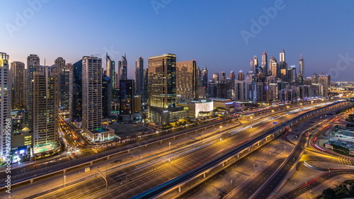 Dubai marina with traffic on sheikh zayed road panorama day to night timelapse lights turn on.