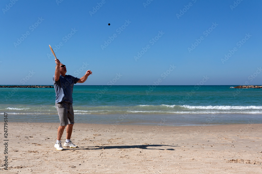 handsome mature man playing tennis on the beach handsome mature man playing tennis on the beach