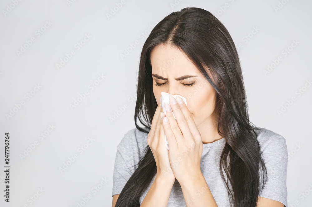 Portrait of a pretty woman having flu. Girl blowing nose standing isolated over white background. Portrait of a pretty woman having flu. Girl blowing nose standing isolated over white background.