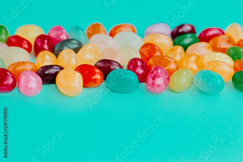 Colorful bean sweet candies on turquoise blue background. Easter concept. Close up. Copy space.