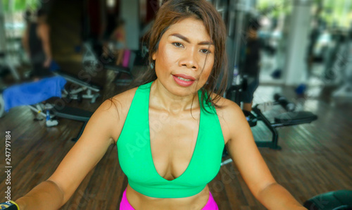 close up face of young determined and focused Asian woman at gym doing workout in elliptical machine sweaty and tired in sport and fitness healthy lifestyle concept