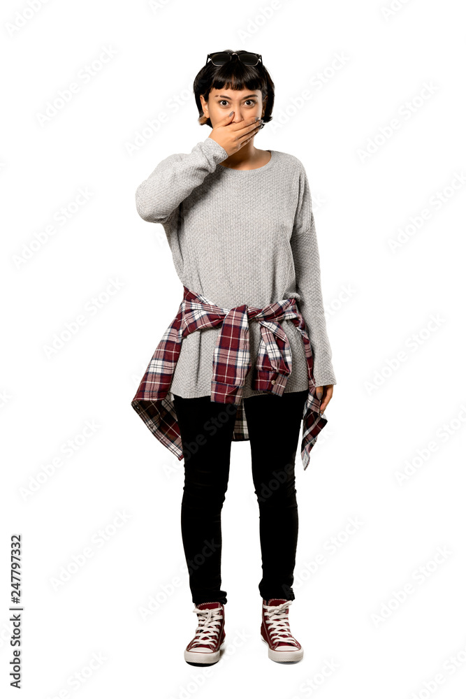 A full-length shot of a Young woman with short hair covering mouth with hands for saying something inappropriate over isolated white background A full-length shot of a Young woman with short hair covering mouth with hands for saying something inappropriate over isolated white background