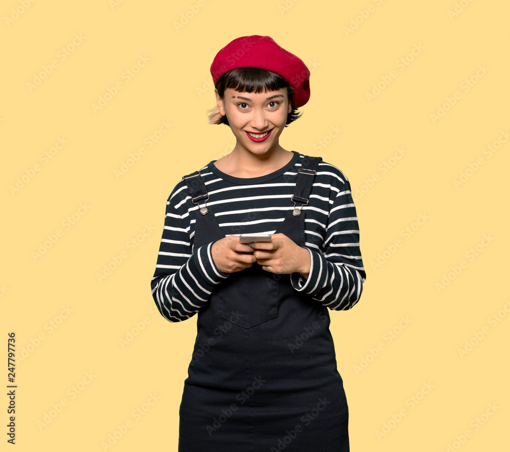 Young woman with beret sending a message with the mobile