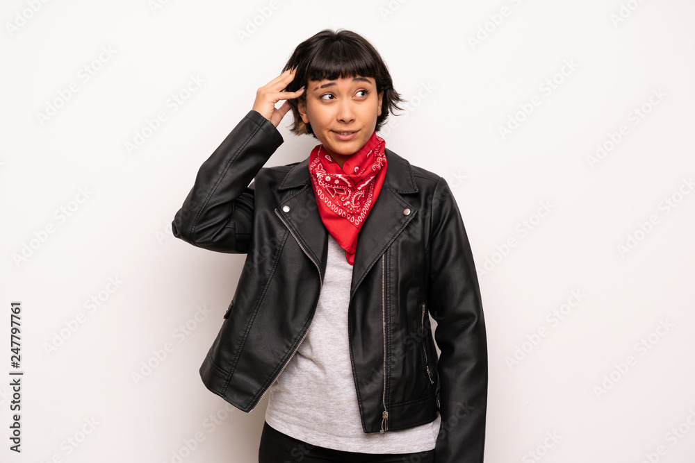 Woman with leather jacket and handkerchief having doubts while scratching head Woman with leather jacket and handkerchief having doubts while scratching head