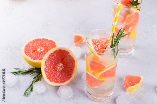 Grapefruit lemonade. Two glasses of refreshing drink, water with grapefruit, rosemary branches and ice. Recipe concept, cocktail