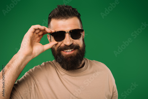 smiling bearded man in sunglasses, isolated on green