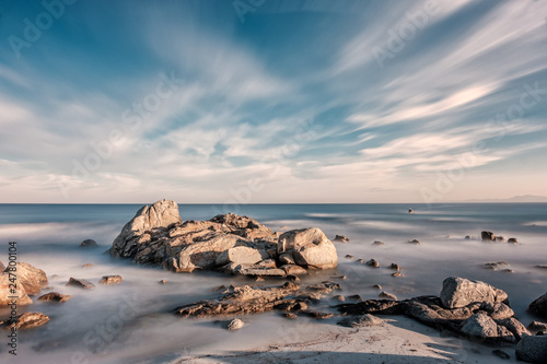 Sea washing over rocks on beach at sunrise in Corsica photo