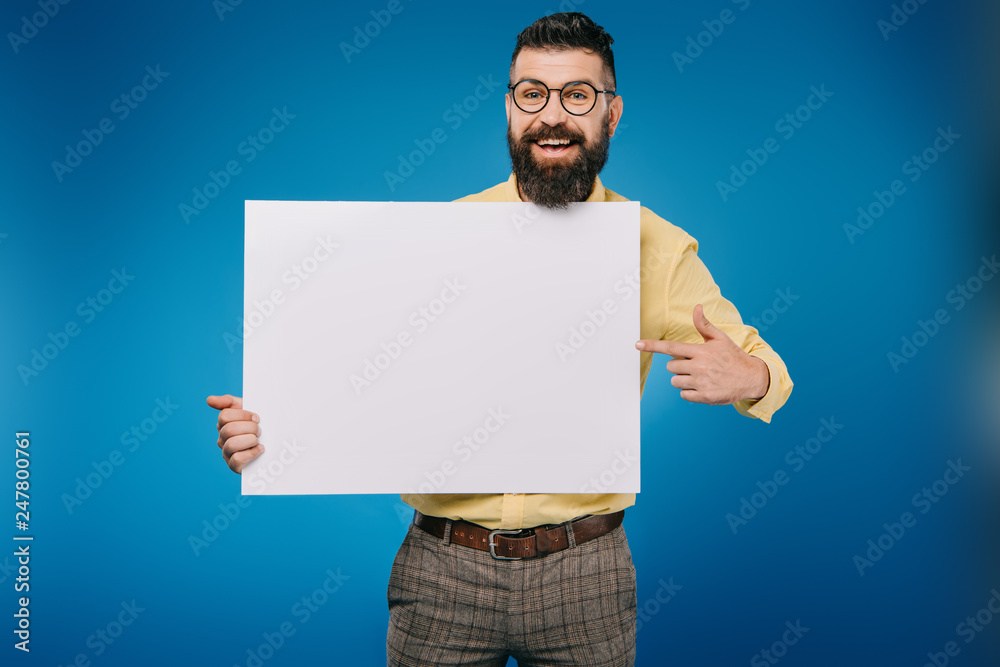 cheerful bearded man pointing at empty board isolated on blue cheerful bearded man pointing at empty board isolated on blue
