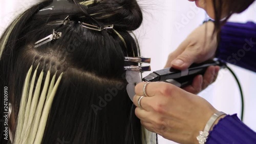 Hairdresser installs the upgrade of hair extension to the client in the salon, Hair extension with keratin concept and close up