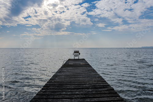 A view on Lake Geneva from a chair on a wooden pontoon.