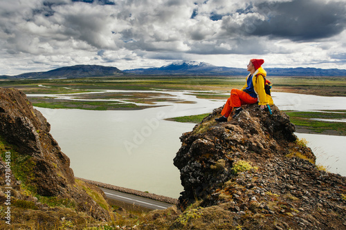 Happy young woman in bright clothes traveling Iceland, enjouing nature photo