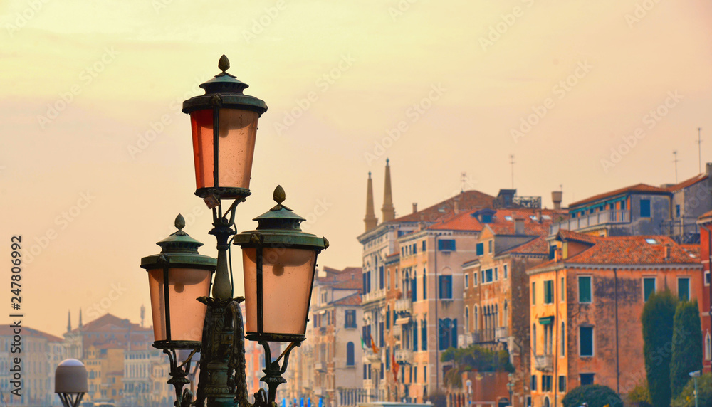detail of an electric street chandelier with the background of old historical buildings overlooking a canal Grande on sunset in Venice, Italy