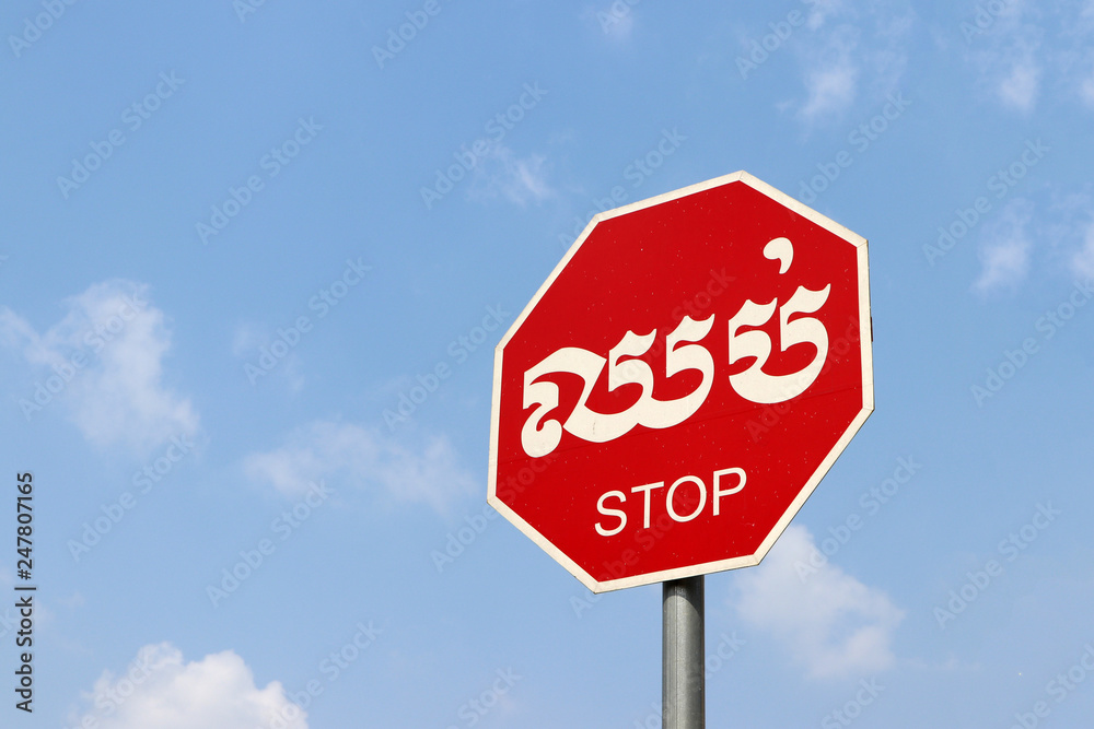 Stop sign on blue sky background in Cambodian language and English. Stop sign on blue sky background in Cambodian language and English.