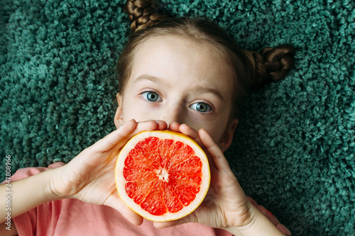 Pretty young girl posing with a red grapefruit.  Healthy lifestyle. photo
