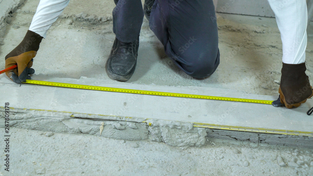 builder doing measures with measuring tape and pencil at construction site builder doing measures with measuring tape and pencil at construction site