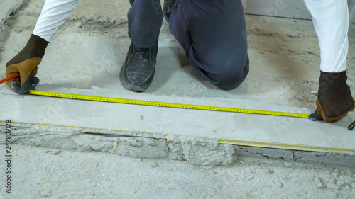 builder doing measures with measuring tape and pencil at construction site