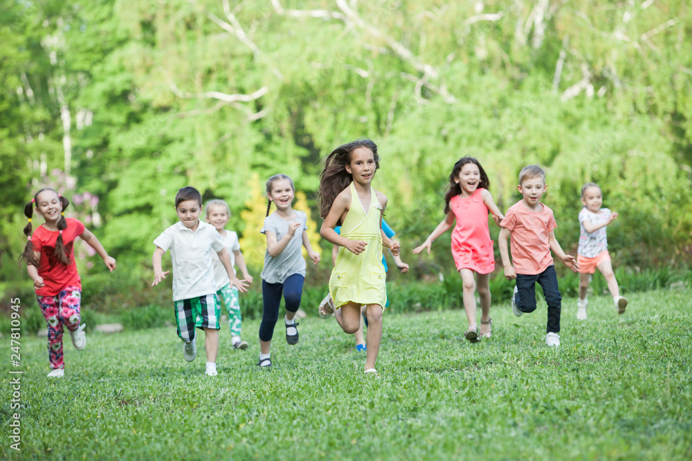 A group of happy children of boys and girls run in the Park on the grass on a Sunny summer day . The concept of ethnic friendship, peace, kindness, childhood. A group of happy children of boys and girls run in the Park on the grass on a Sunny summer day . The concept of ethnic friendship, peace, kindness, childhood.