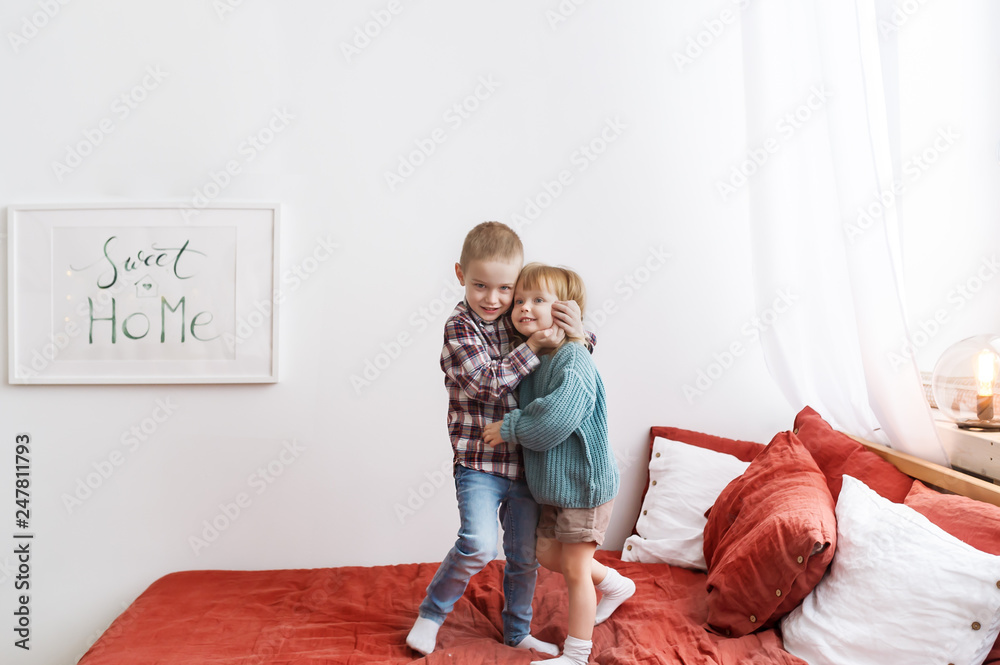 Brother and sister cuddling, playing together at home