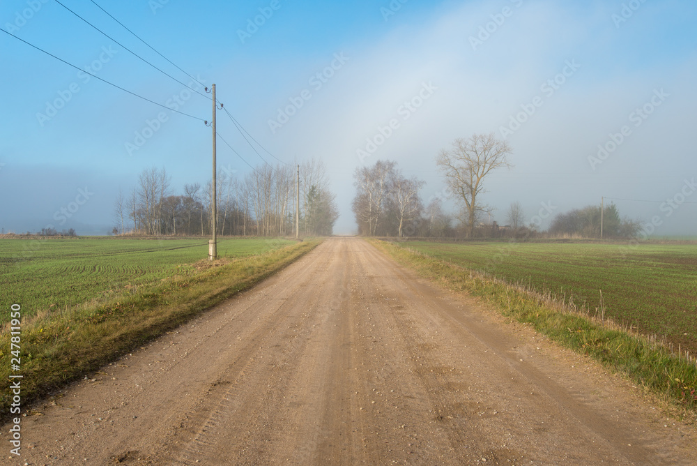 empty country gravel road with mud puddles and bumps