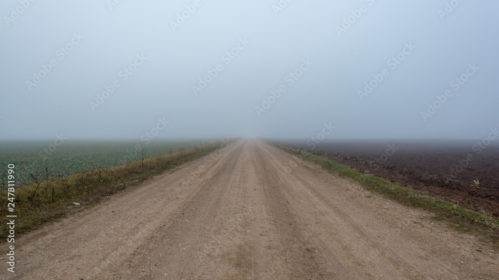 empty country gravel road with mud puddles and bumps