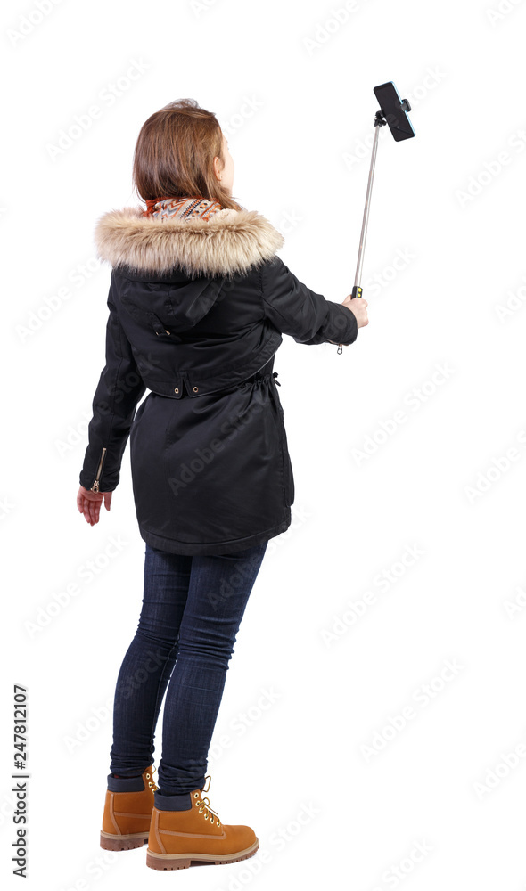 back view of standing young beautiful girl in winter jacket with smartphone in the hands of. back view of standing young beautiful girl in winter jacket with smartphone in the hands of.