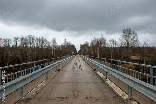 empty country gravel road with mud puddles and bumps