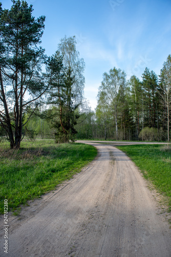 empty country gravel road with mud puddles and bumps