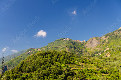 San Bernardino village on the top of green hills with blue sky copy space background, view from Corniglia, National park Cinque Terre, La Spezia province, Liguria, Italy photo