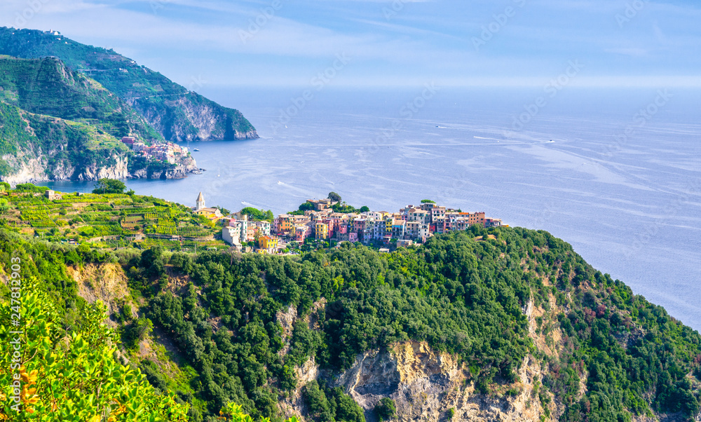 Corniglia traditional typical Italian village with colorful buildings on rock cliff and Manarola, Genoa Gulf, Ligurian Sea, blue sky background, National park Cinque Terre, La Spezia, Liguria, Italy