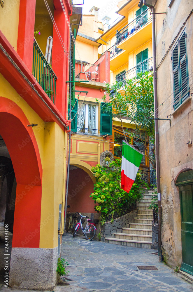 Typical small italian yard with buildings houses, stairs, shutter window and italian flag in Monterosso village, National park Cinque Terre, La Spezia province, Liguria, Italy
