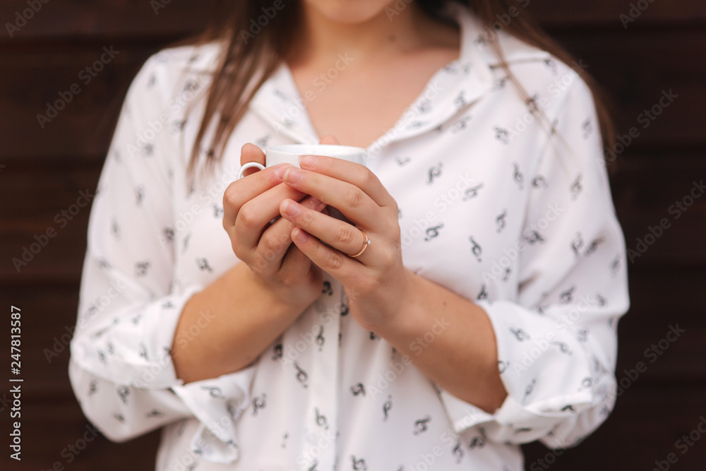 Beautiful girl hold a cup of coffee. White shirt. Wooden background Beautiful girl hold a cup of coffee. White shirt. Wooden background