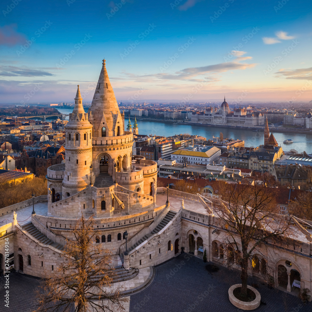 Naklejka premium Budapeszt, Węgry - główna wieża słynnego Baszty Rybackiej (Halaszbastya) z góry z budynkiem Parlamentu i rzeką Dunaj w tle w słoneczny poranek