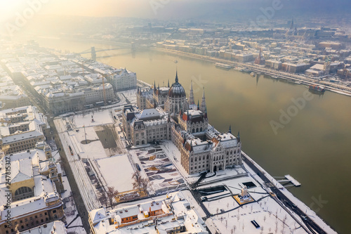 Budapest, Hungary - Aerial view of the snowy Parliament of Hungary by River Danube on a foggy winter morning with Szechenyi Chain Bridge, Buda Castle Royal Palace and Fisherman's Bastion at background