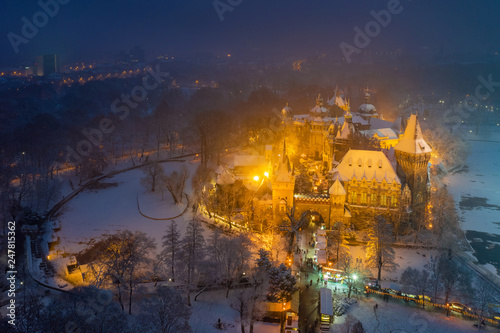 Budapest, Hungary - Aerial view of snowy Vajdahunyad castle in City Park with lovely Christmas market at blue hour