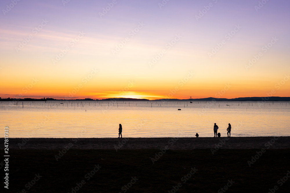 Group of people walking on the beach at sunset. Beautiful marine landscape with calm sea. Rias Baixas, Galicia, Spain