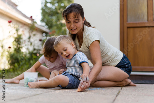 Mother with children drawing with chalk