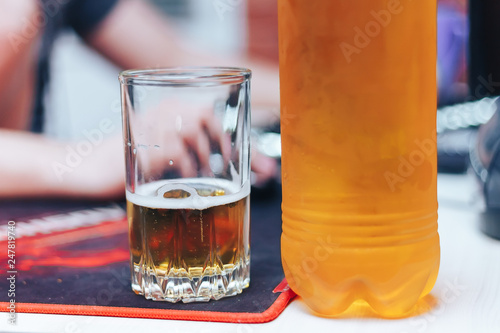 beer in glass and plastic bottle on table man beahind at home photo