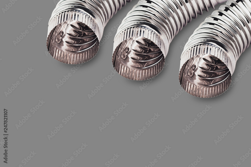 Three chrome corrugated elbows of pipes for air, water, oil or gas in corners on gray background with copy space for your text Three chrome corrugated elbows of pipes for air, water, oil or gas in corners on gray background with copy space for your text